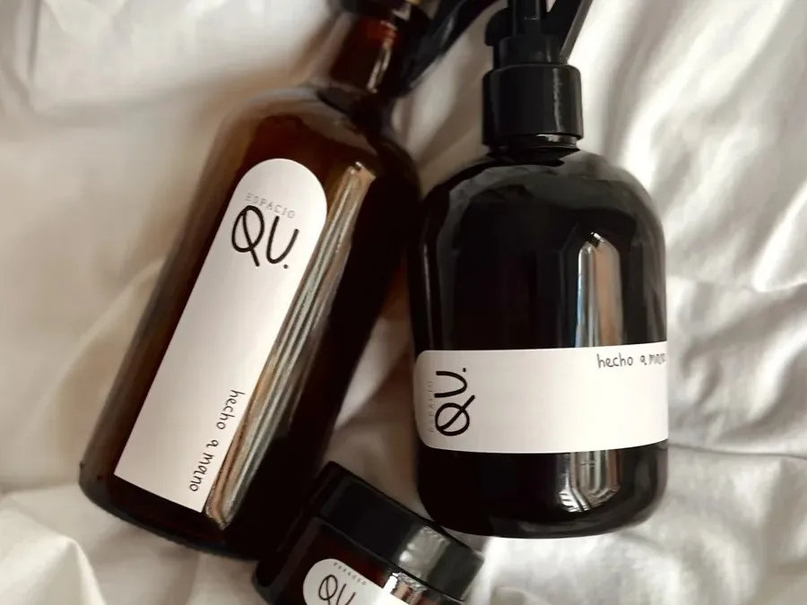 Difusor, homespray y vela de Espacio QU sobre una sábana blanca